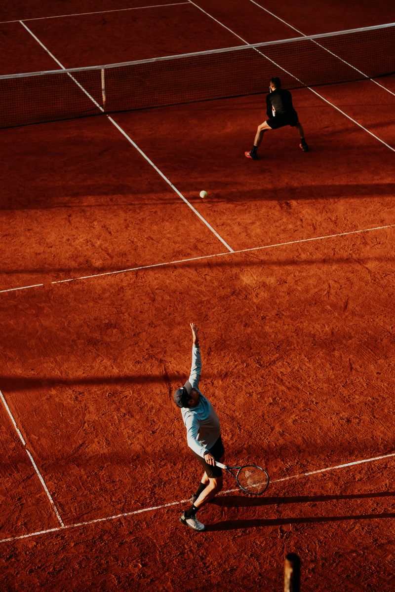 Vista aérea de un partido de tenis en una cancha de polvo de ladrillo